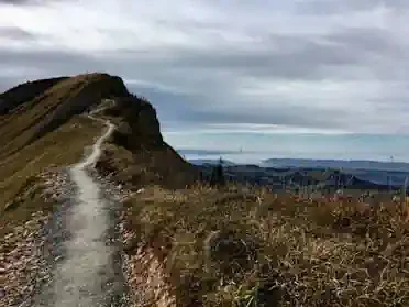 Steiniger Weg Wanderweg entlang eines Bergrückens mit Aussicht auf eine hügelige Landschaft.